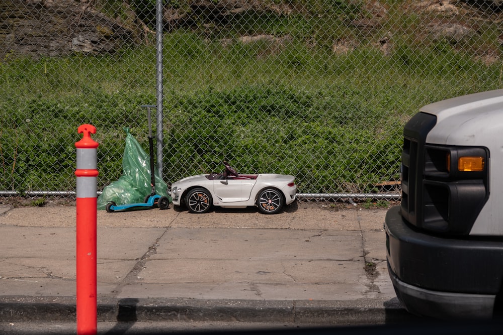 a car parked on the side of a road next to a fence