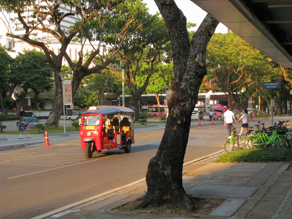 a tuk tuk driving down a street next to a tree