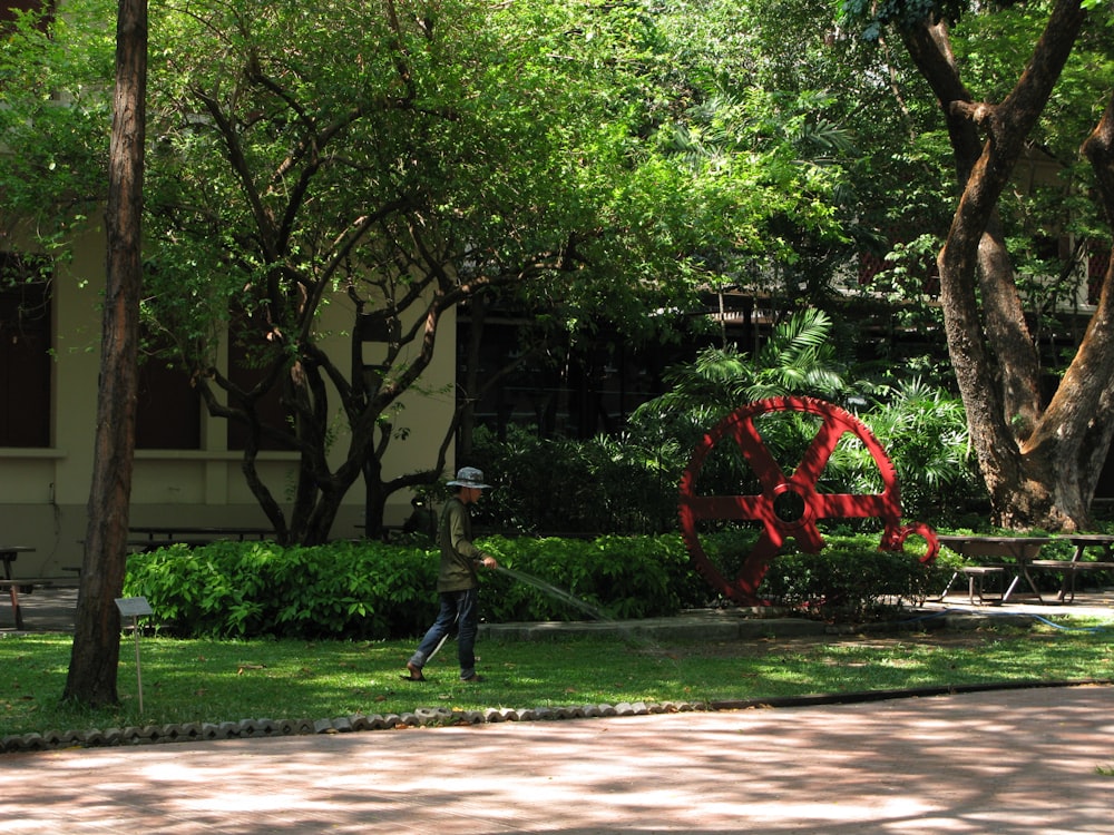 a man walking past a red sculpture in a park
