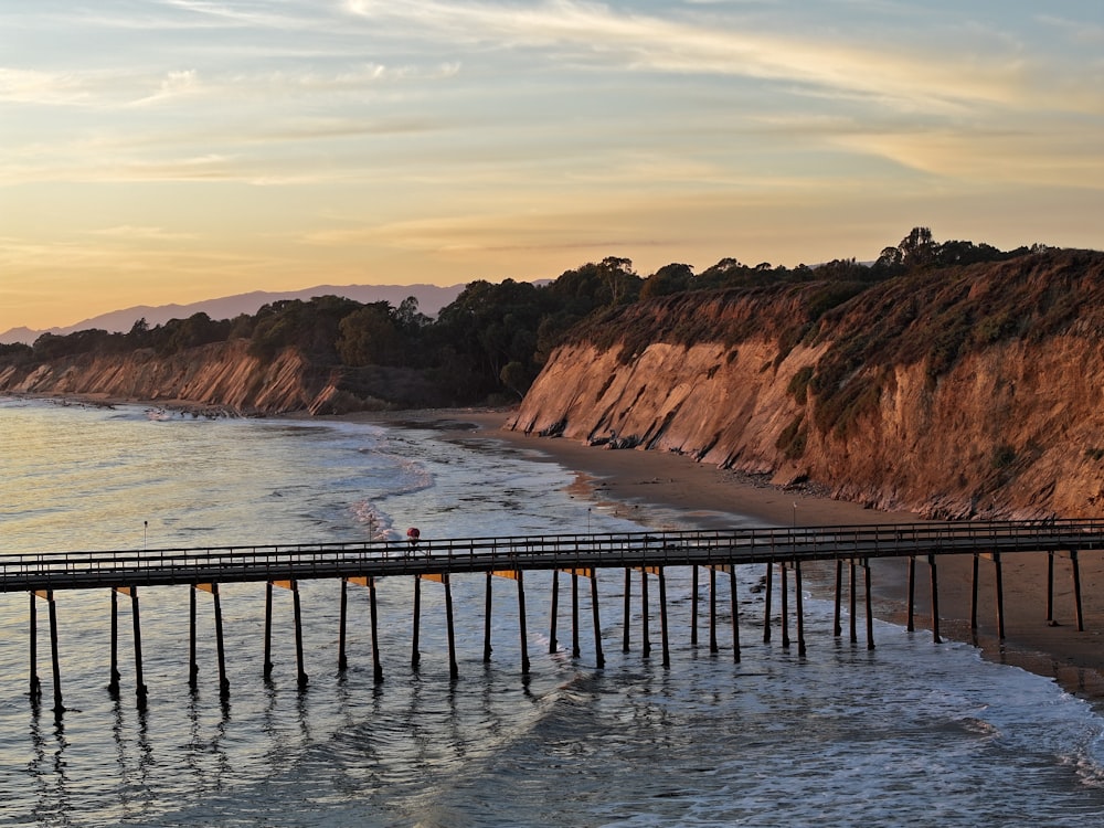 ein Pier an einem Strand neben einer Klippe