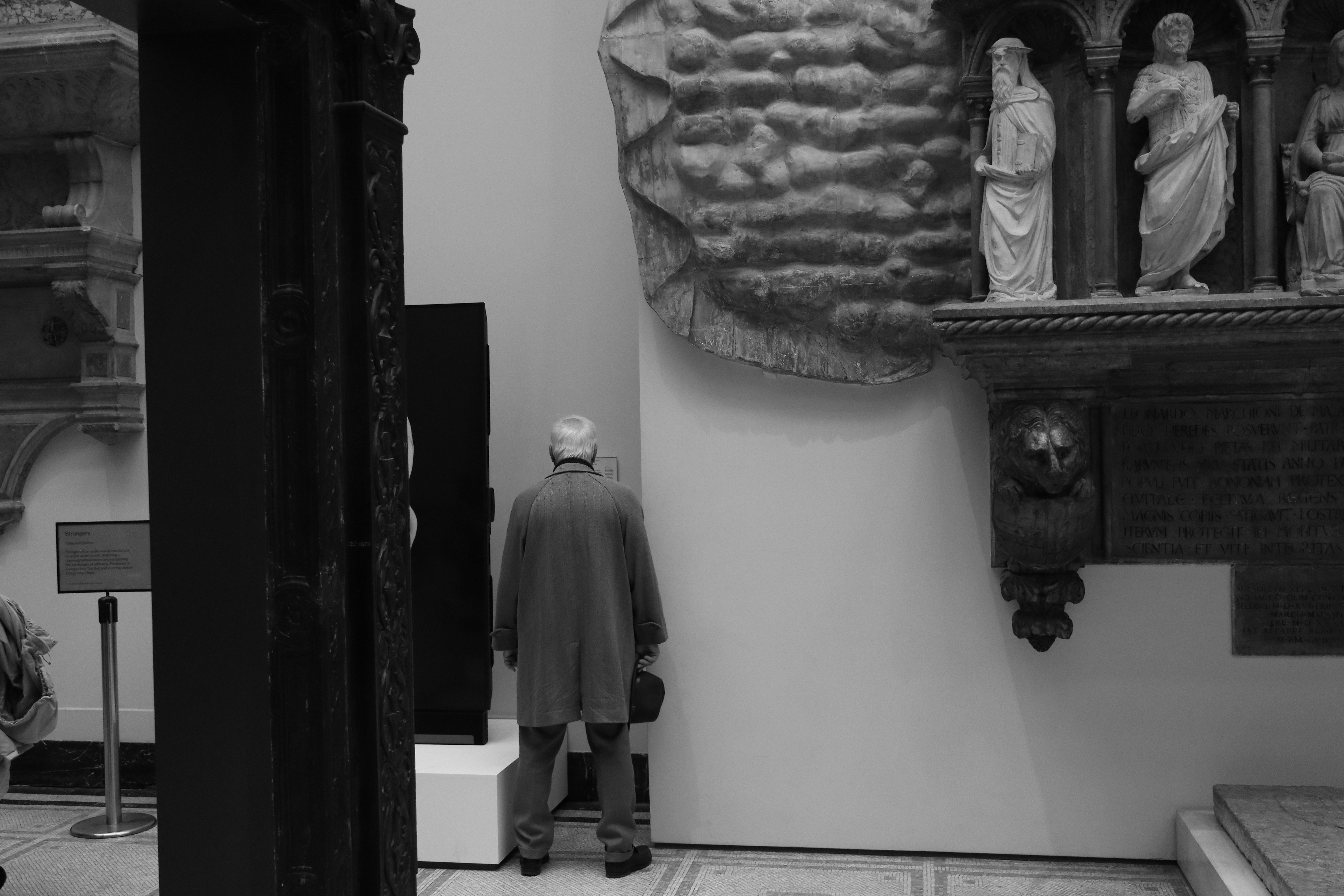 銅像の前に立つ男性の白黒写真