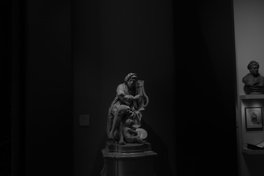 a black and white photo of a statue in a dark room