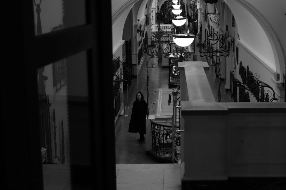 a black and white photo of a woman walking down a hallway