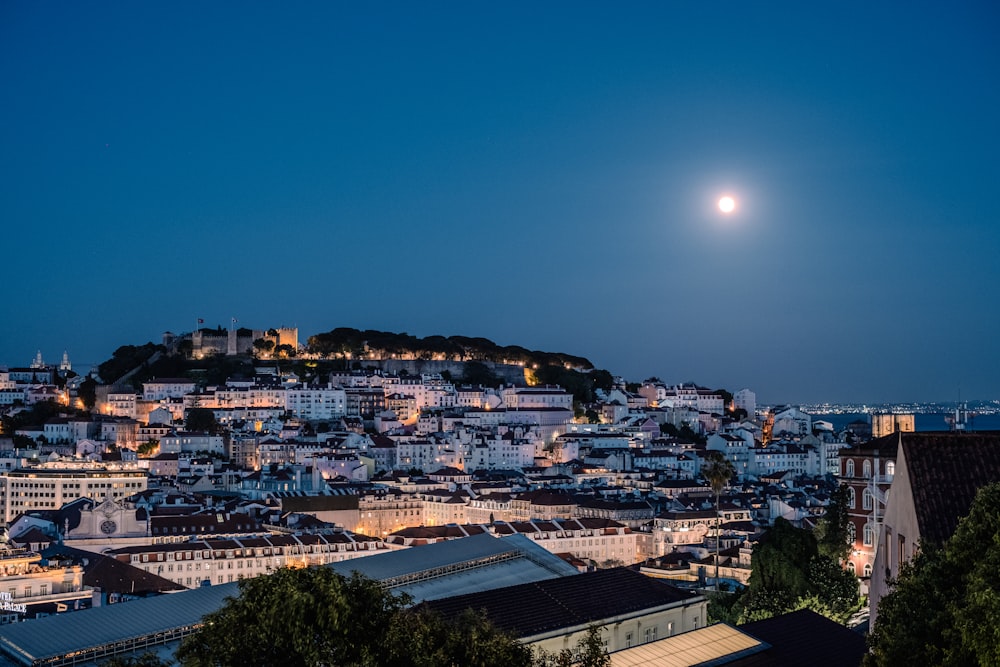 a full moon rises over a city at night
