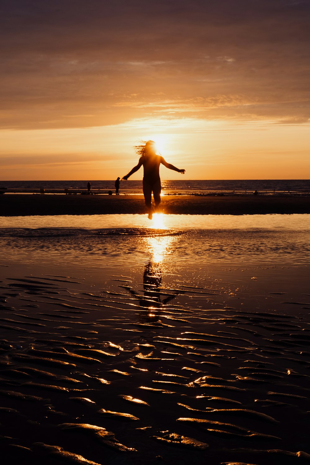 una persona de pie en una playa al atardecer