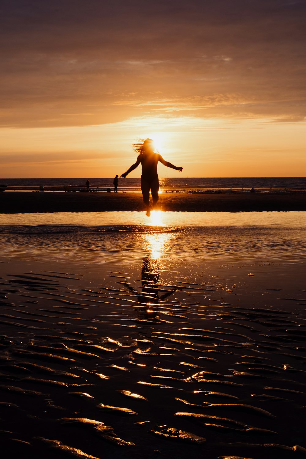 a person standing on a beach at sunset