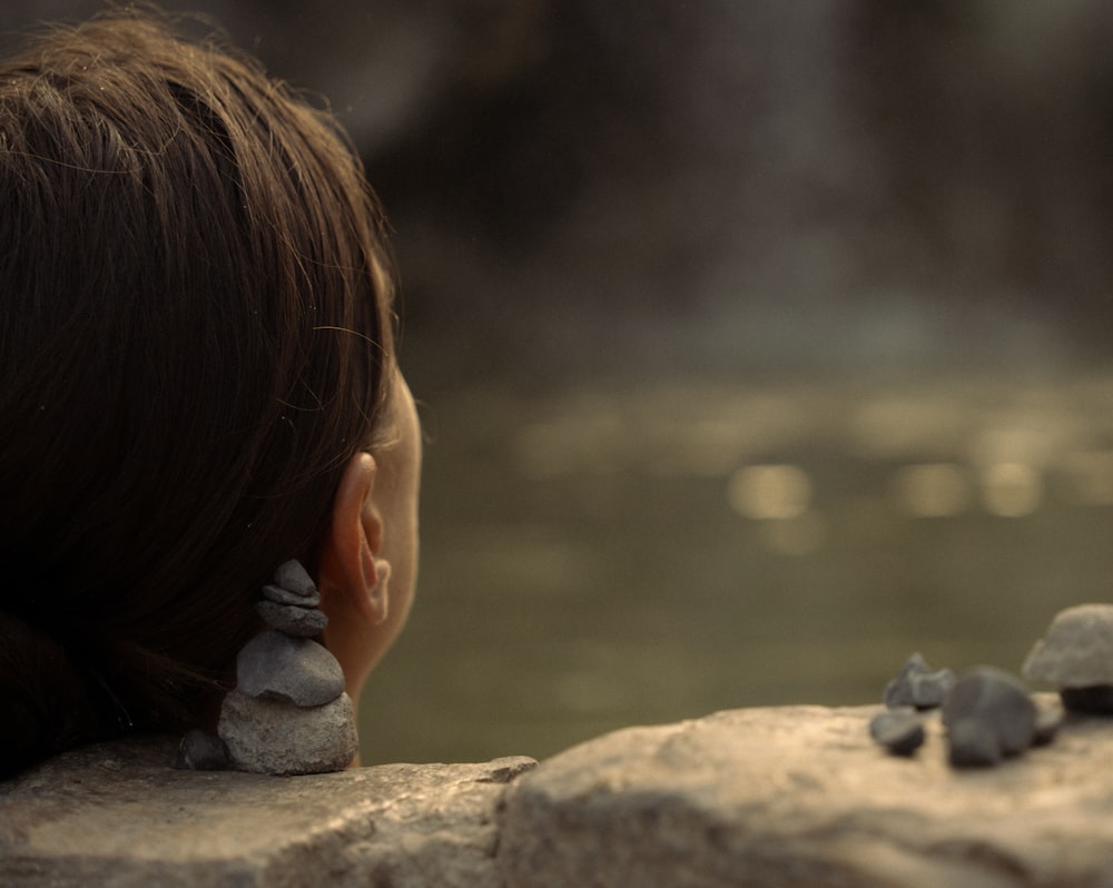 una donna seduta su una roccia vicino a uno specchio d'acqua