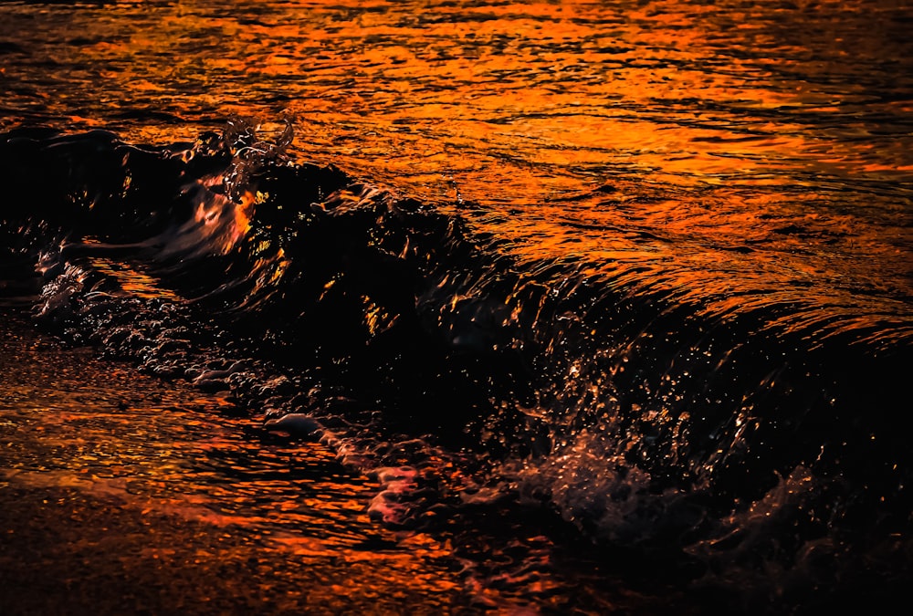a wave is coming in to shore at sunset