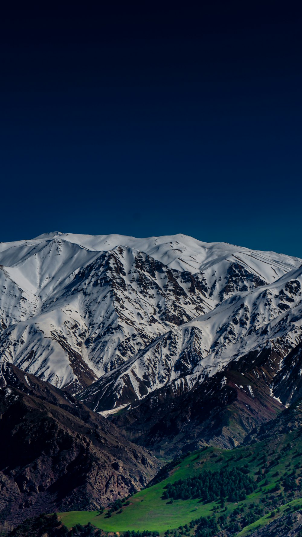 a snowy mountain range with a green valley below