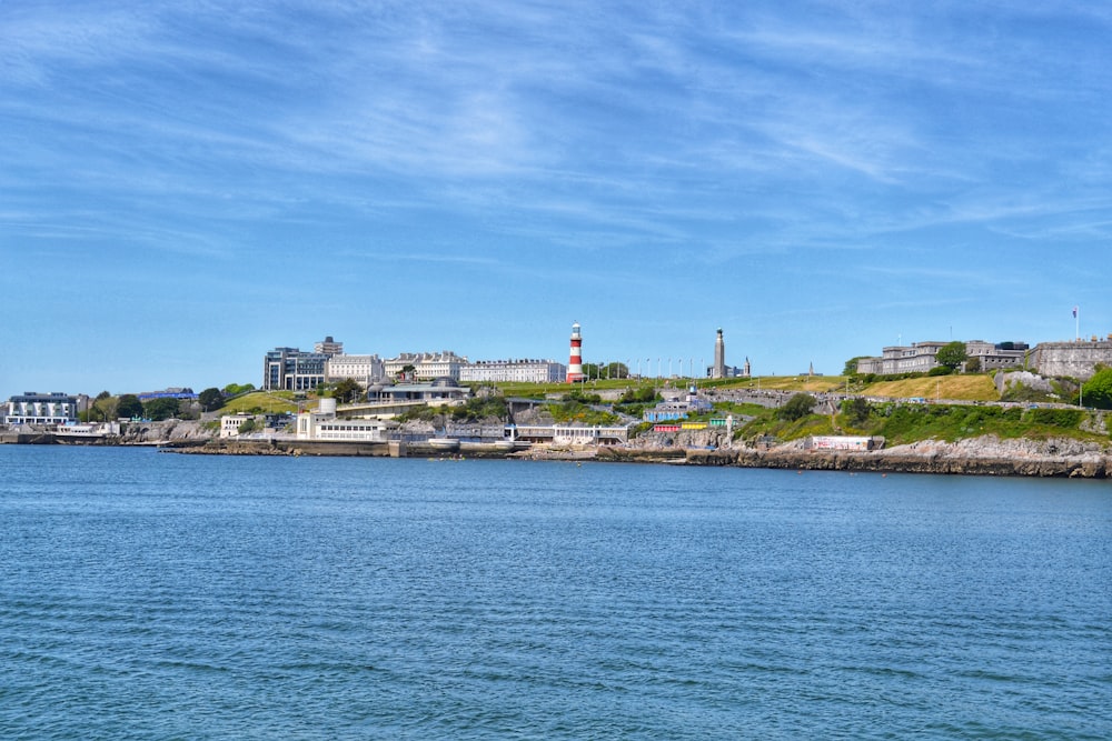 a body of water with a lighthouse on a hill in the background