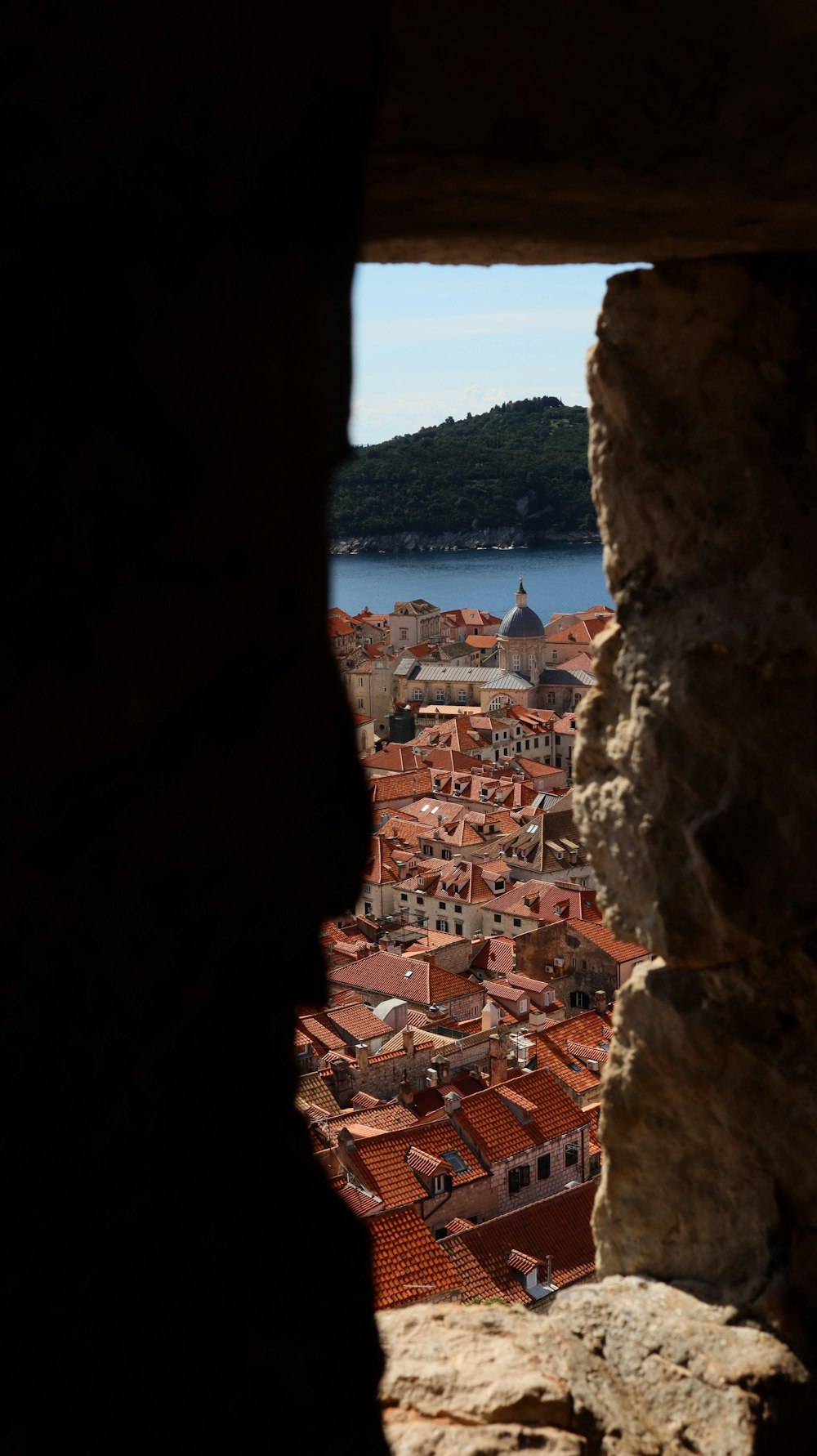 a view of a city through a hole in a stone wall