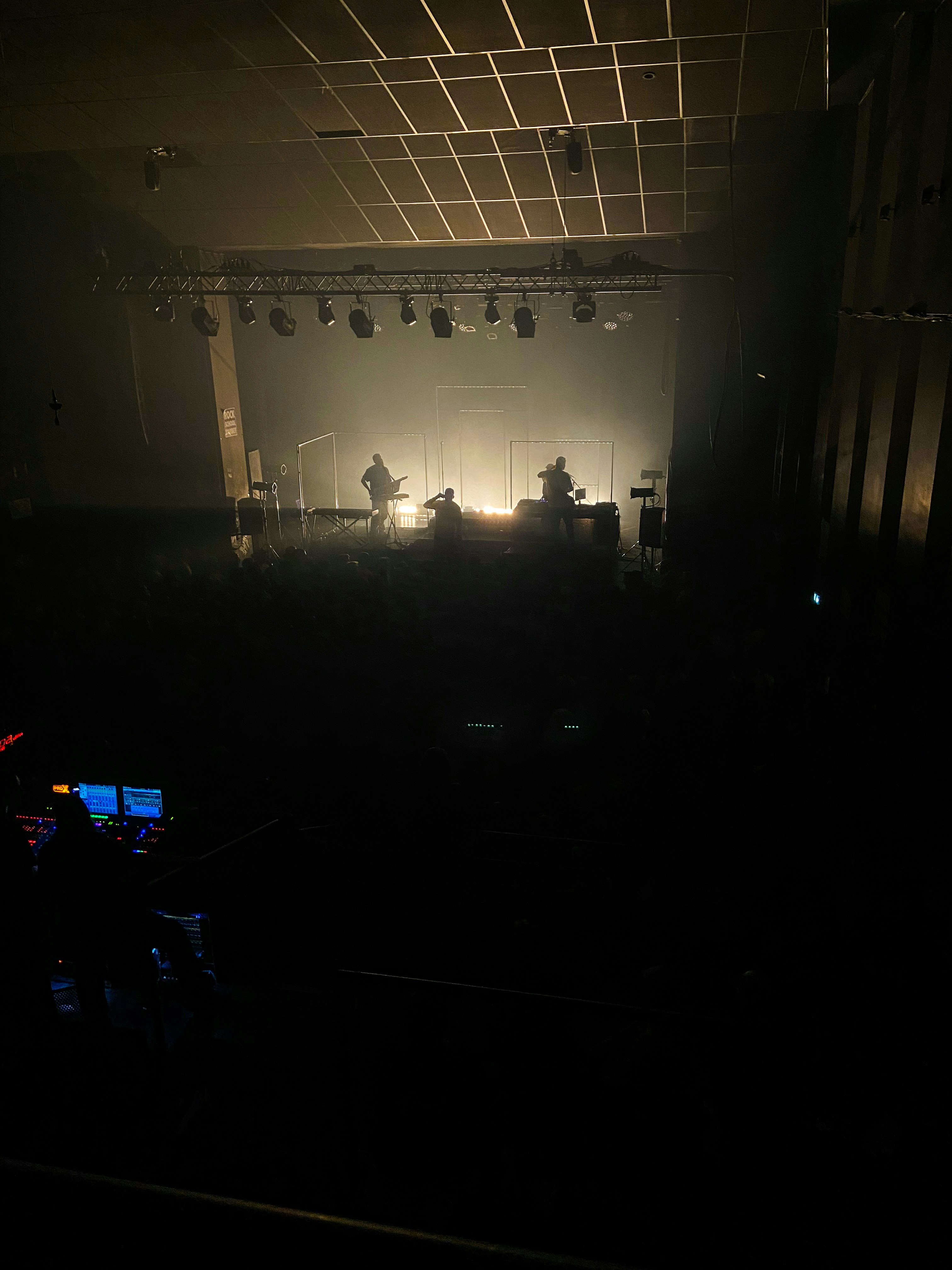 Musician performing on stage with dramatic backlighting, dark silhouette against glowing backdrop