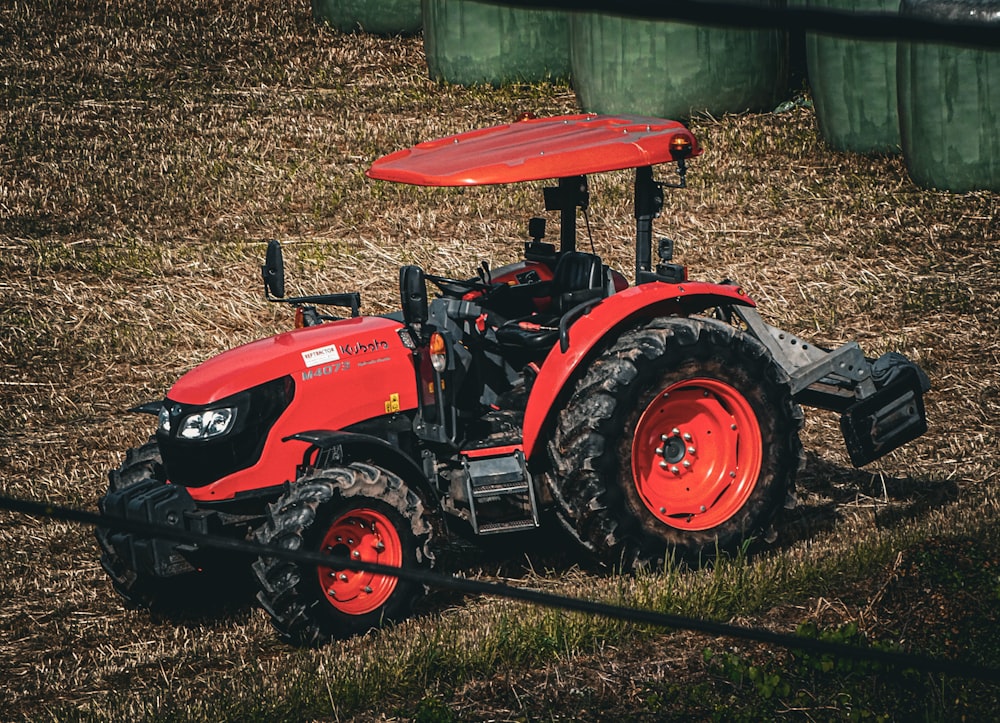 a red tractor parked on top of a dry grass field