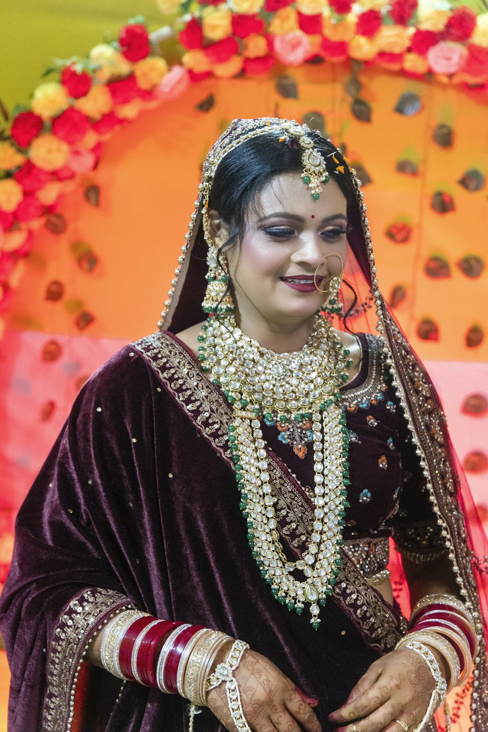 a woman in a bridal outfit standing in front of a decorated umbrella