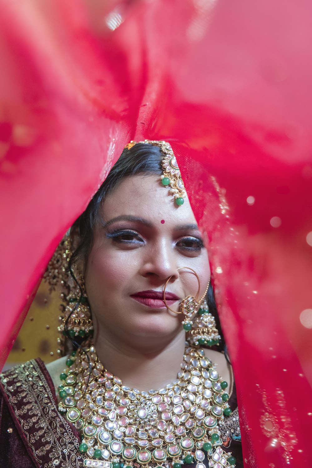 a woman wearing a red veil and jewelry