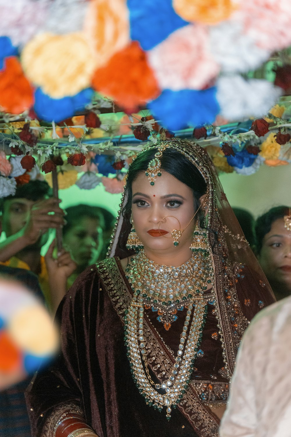 a woman dressed in a bridal outfit standing under an umbrella