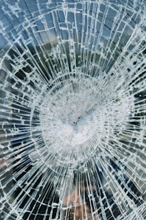 a broken glass window with a clock on it