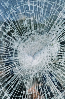 a broken glass window with a clock on it