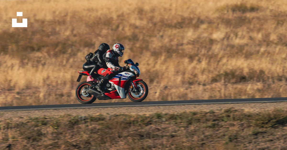 A man riding a red motorcycle down a road photo – Free Aktobe Image on ...