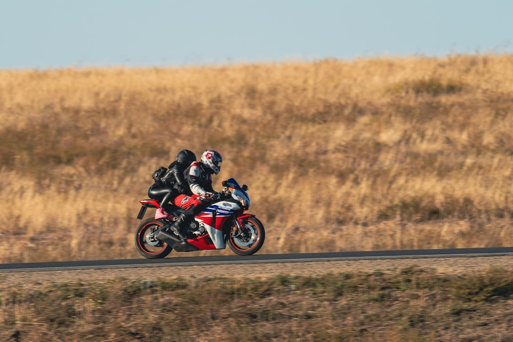 a man riding a red motorcycle down a road