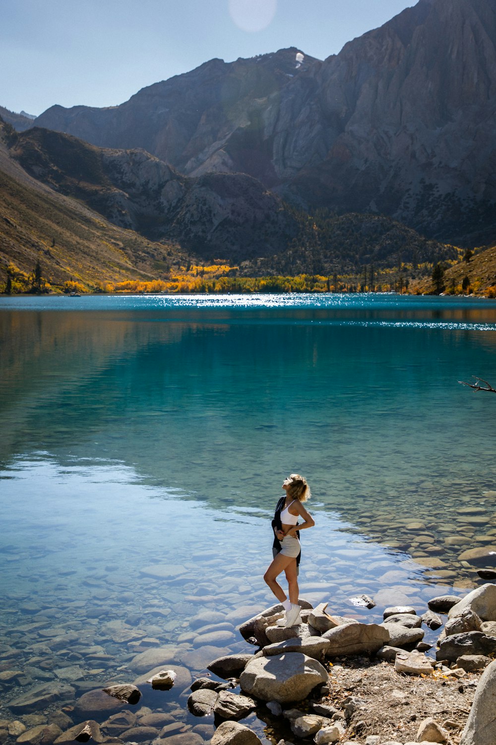 a woman in a bathing suit standing on rocks near a body of water