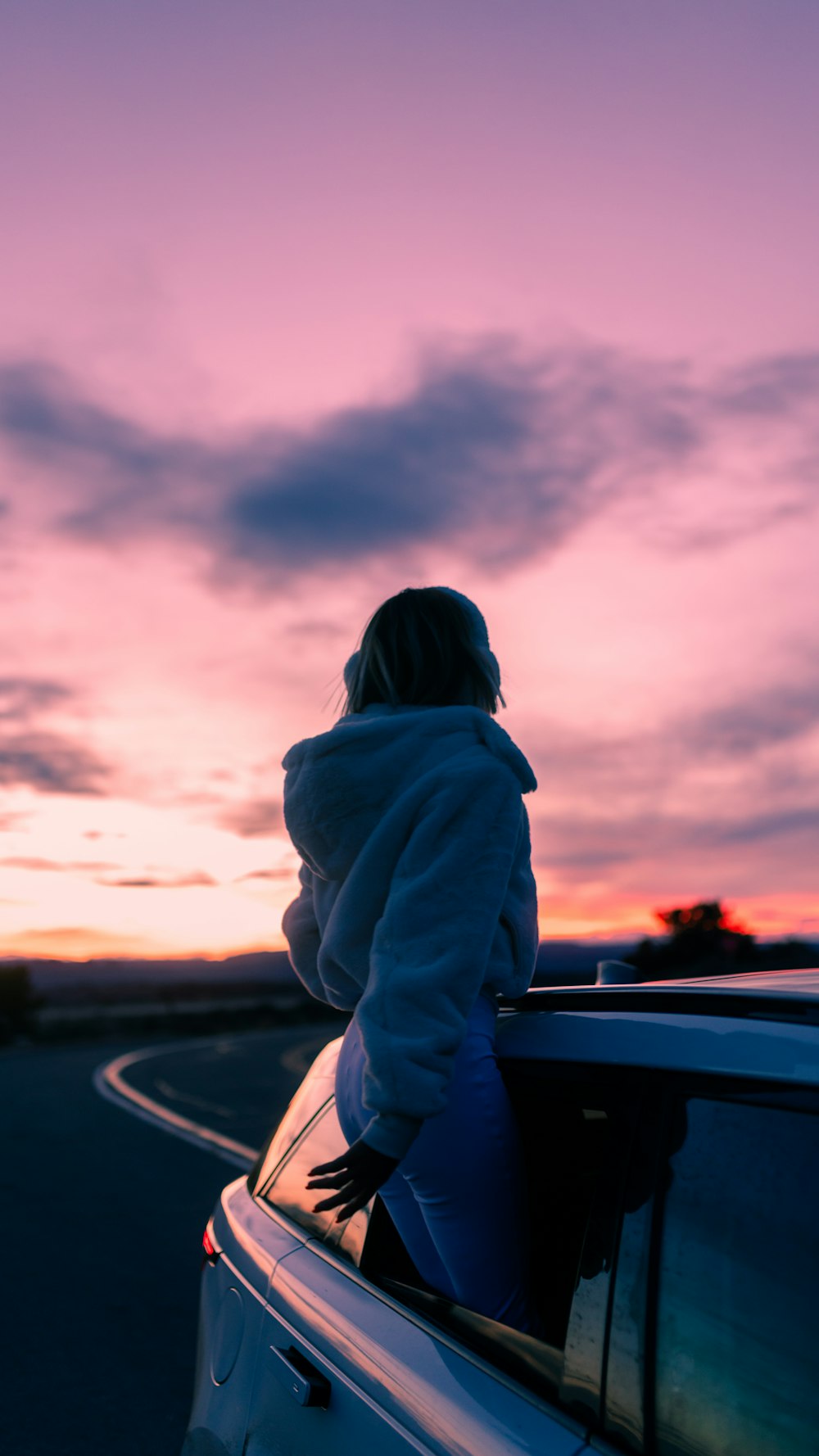 a woman in a hoodie leaning out of a car window