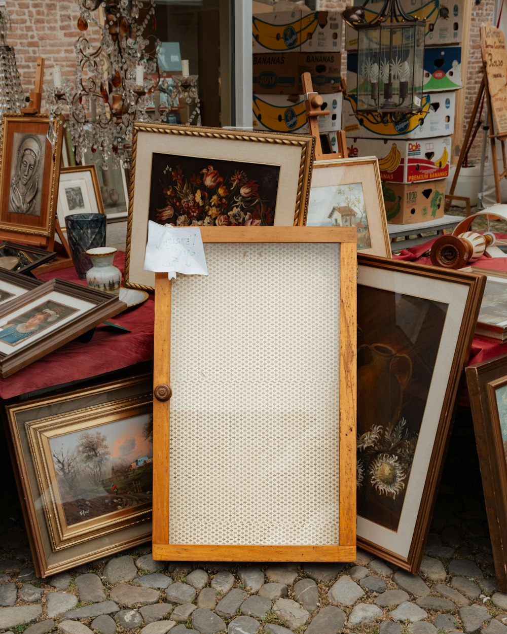 a pile of framed pictures sitting on top of a stone floor