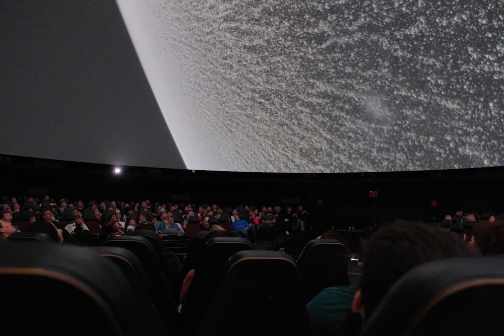 a crowd of people sitting in front of a projector screen