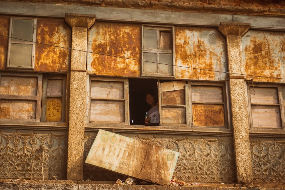 a man looking out of a window of a run down building