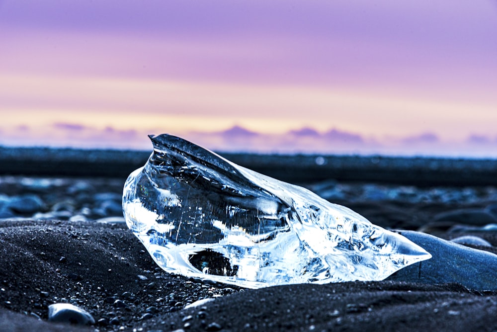 a piece of ice sitting on top of a black sand beach