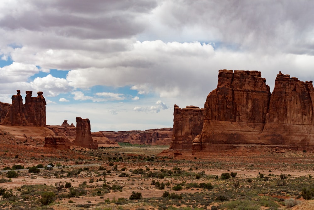 a desert landscape with rock formations under a cloudy sky
