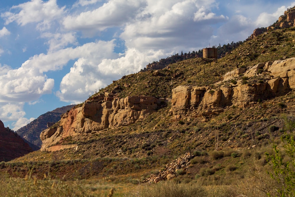 a mountain side with a few clouds in the sky