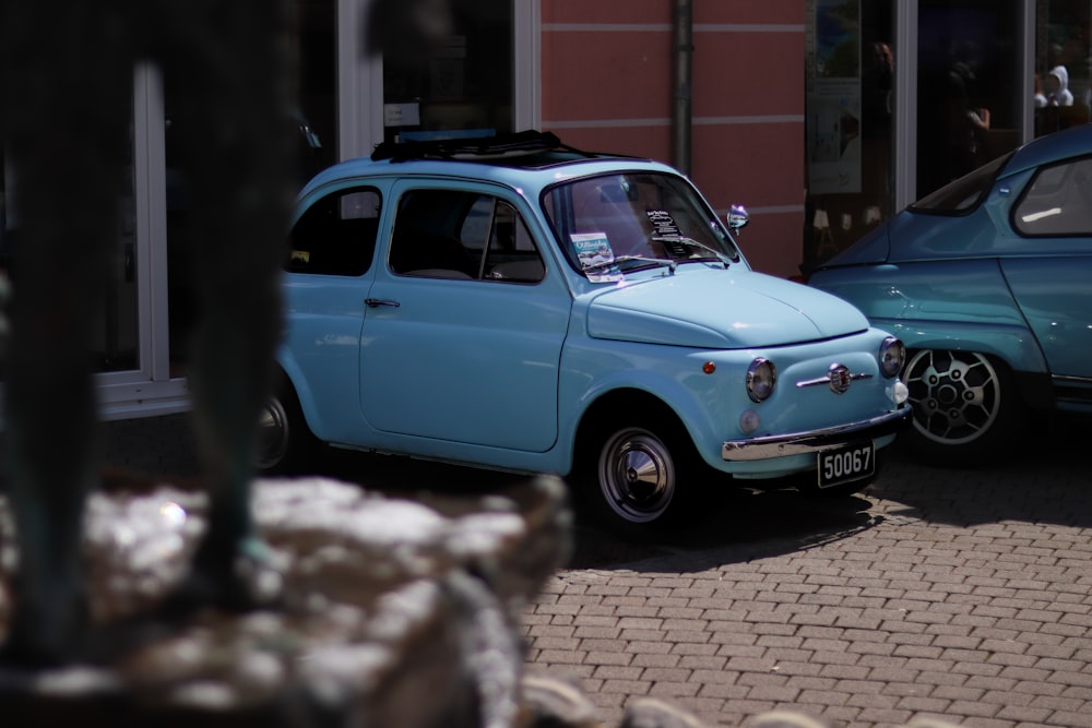 a small blue car parked in front of a building