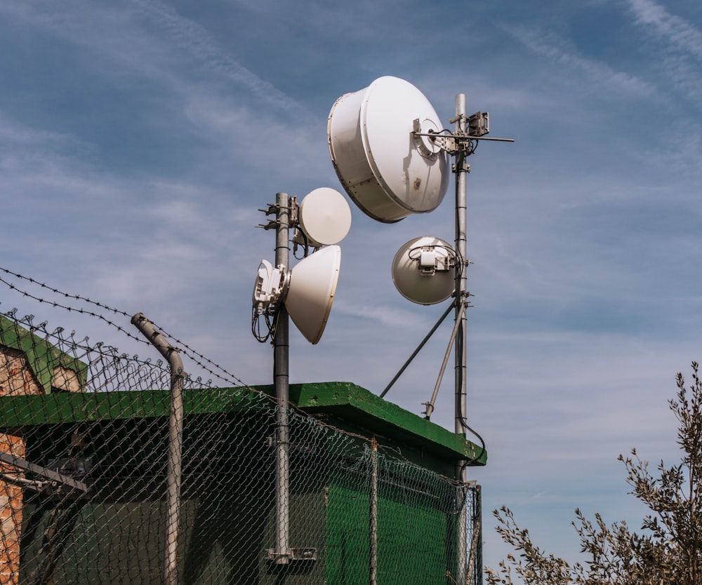 a couple of antennas sitting on top of a green fence