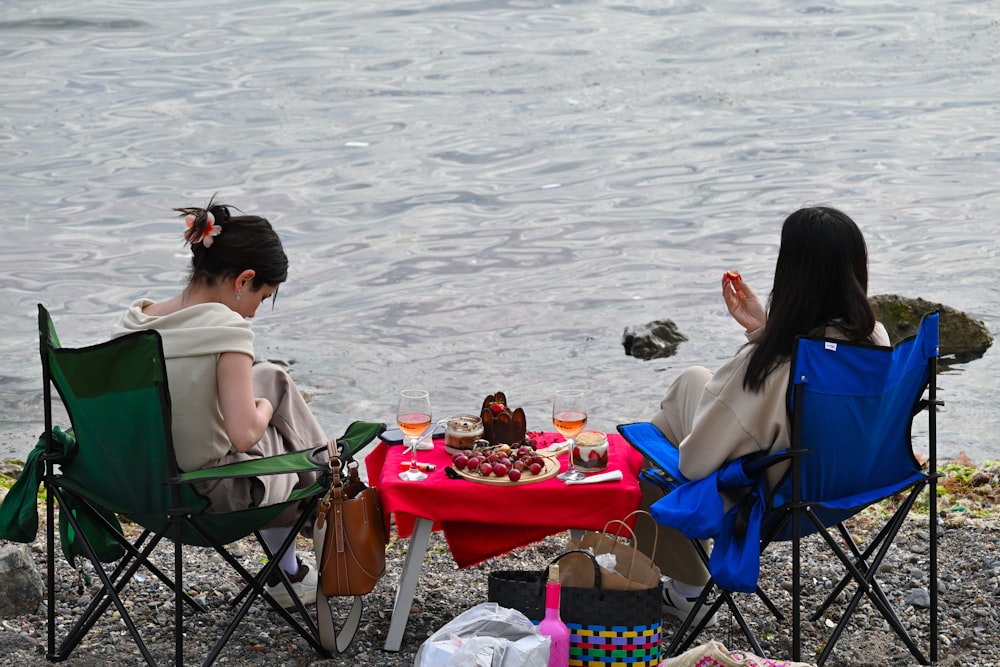 a couple of women sitting next to each other on top of a beach