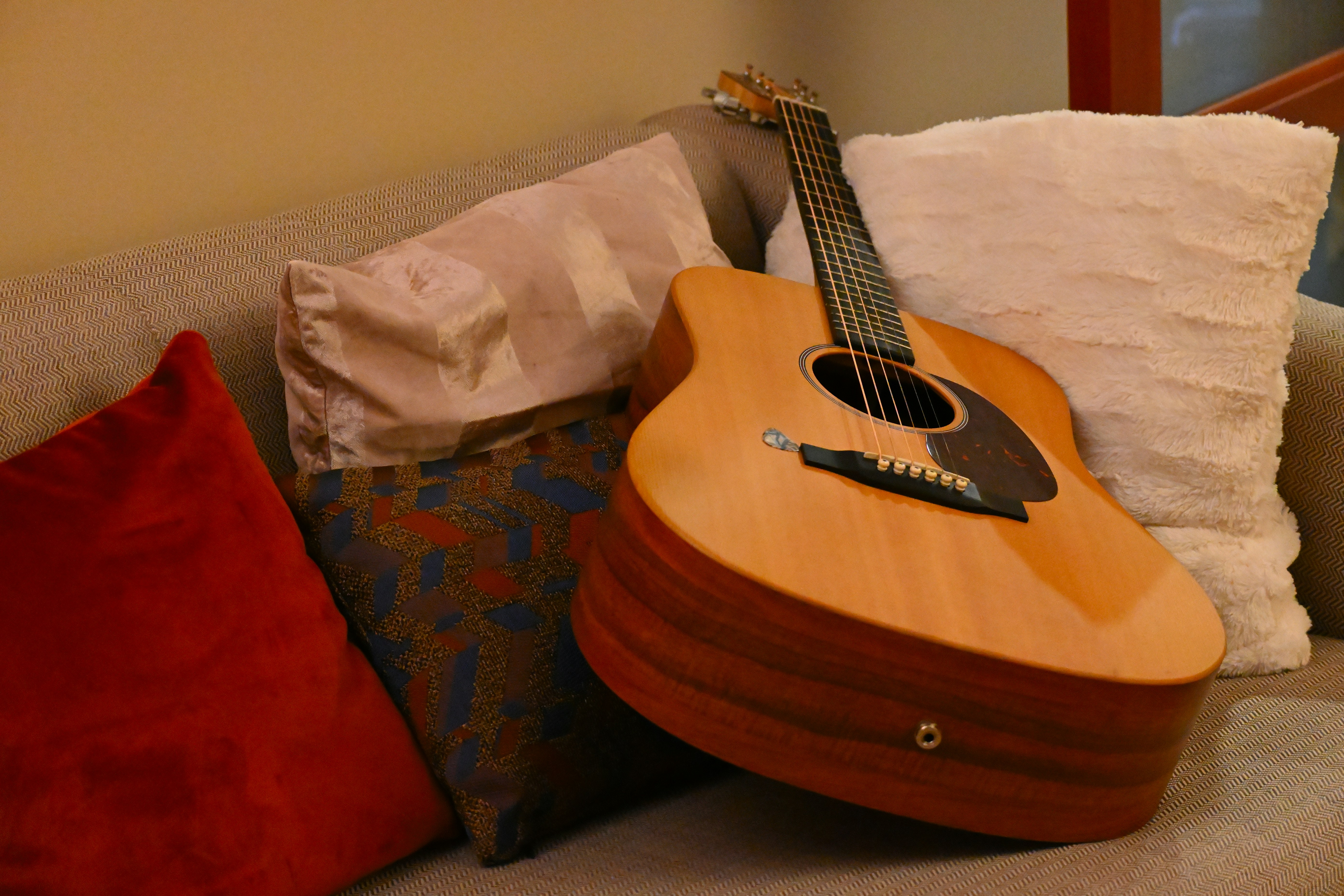 a guitar sitting on top of a couch next to pillows