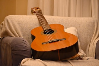 a guitar sitting on top of a couch next to a pillow