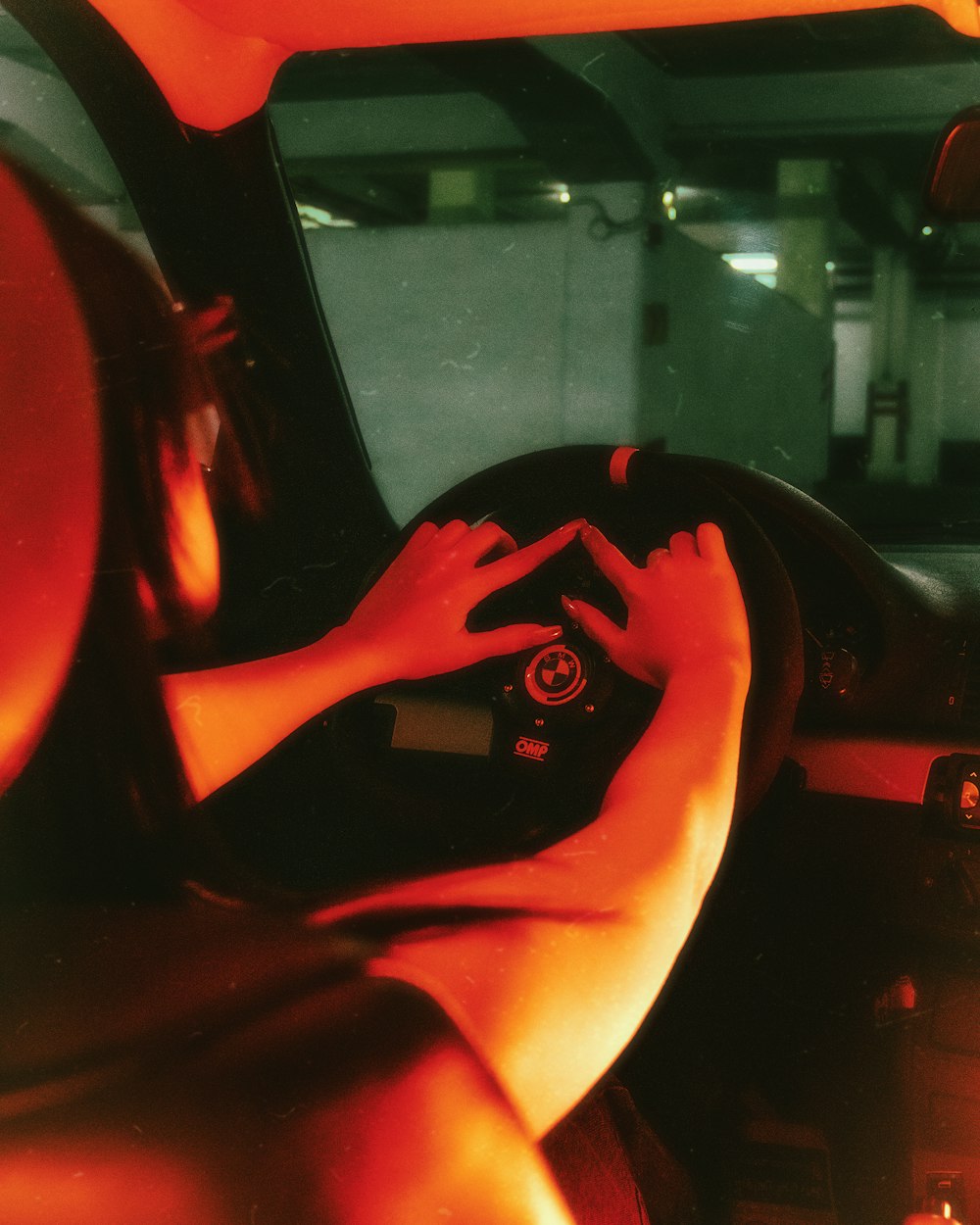 a woman sitting in a car with her hands on the steering wheel