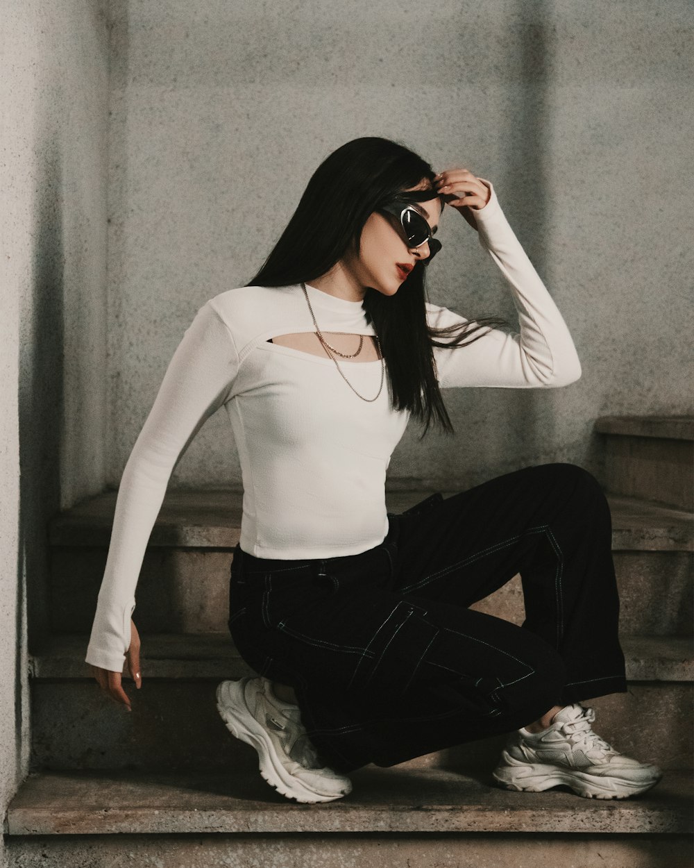 a woman in white shirt and black pants sitting on steps