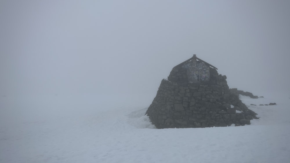 a stone structure in the middle of a snowy field