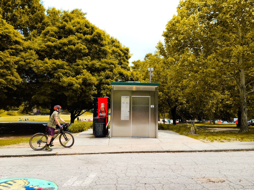 a man riding a bike past a public phone booth