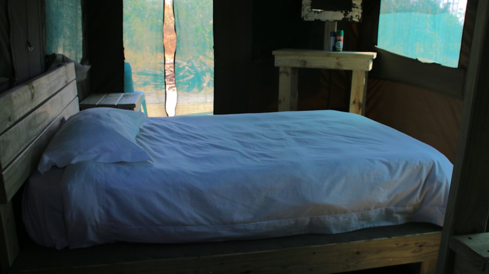una cama con edredón blanco y cabecero de madera
