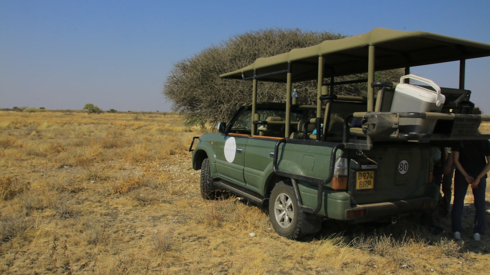 a safari vehicle parked in the middle of a dry grass field