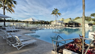 a large swimming pool surrounded by lounge chairs and palm trees