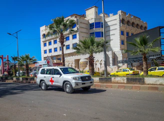 a white suv driving down a street next to a tall building