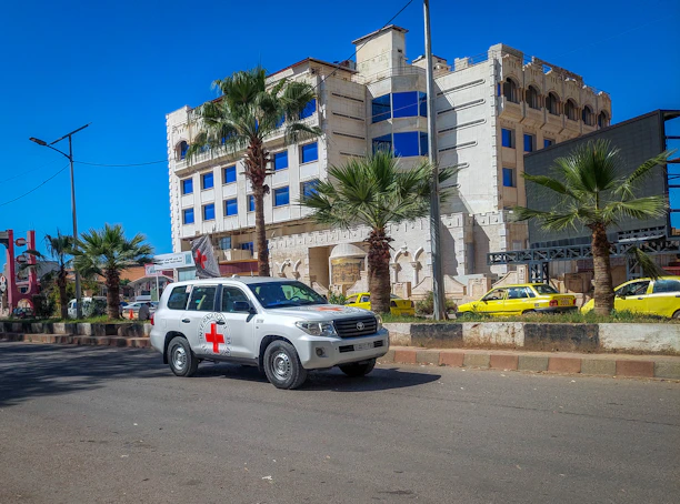a white suv driving down a street next to a tall building
