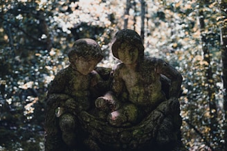 a couple of statues sitting in the middle of a forest
