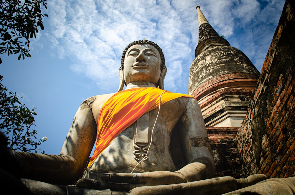 a large buddha statue sitting next to a brick building