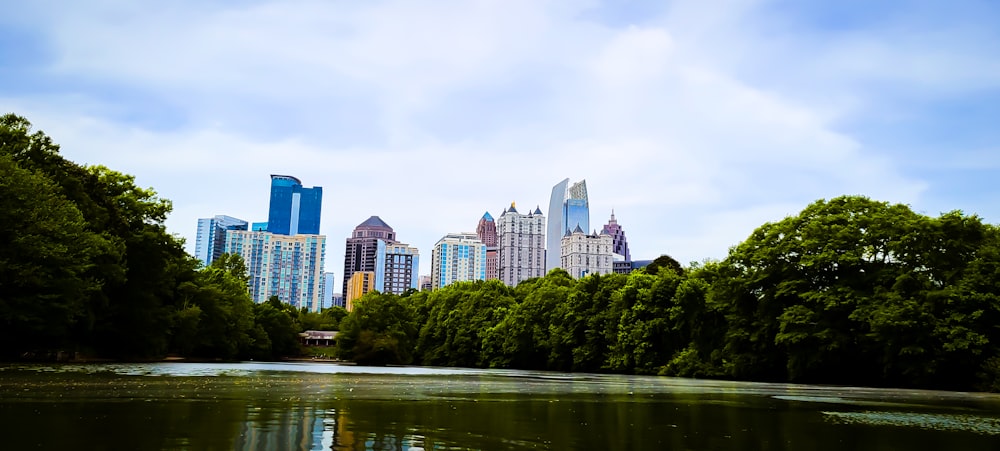 a body of water surrounded by trees and tall buildings