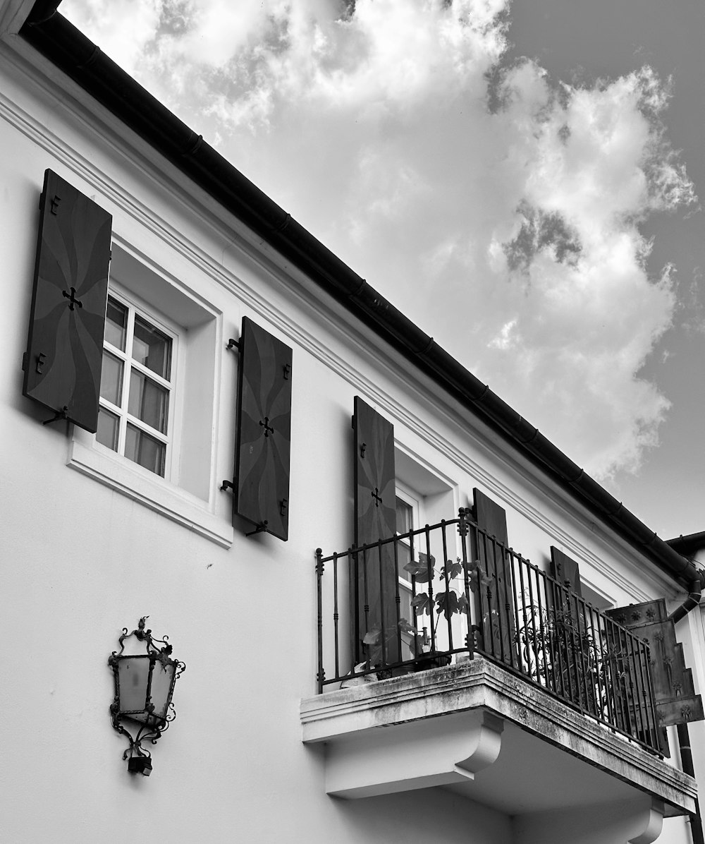 a white building with black shutters and a balcony